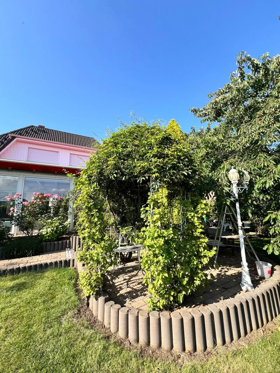 Gepflegter Rosenbogen im Rondell mit Palisadeneinfassung – Gartenpflege Goslar