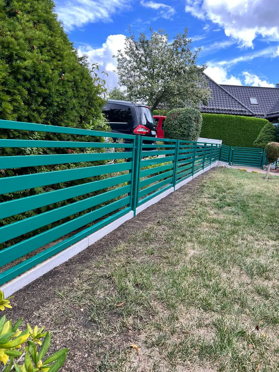 Neu montierter grüner Zaun auf Betonsockel am Rasen – Gartenbau Goslar